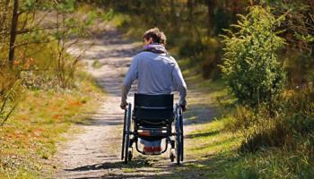 Una persona se desplaza en silla de ruedas por un camino sin asfaltar.