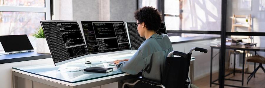 Una mujer con discapacidad trabaja programando delante de varios ordenadores | Foto: Andrei Popov 